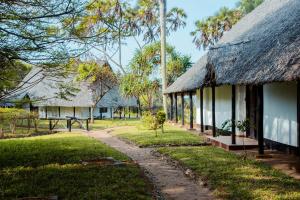 a house with a thatched roof and a path at Amani Beach Resort in Dar es Salaam