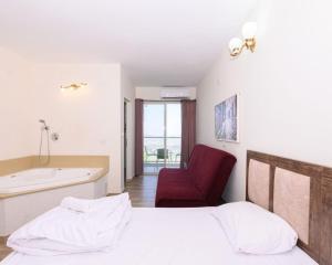 a bedroom with a bed and a bathtub and a red chair at האלפים של הכרמל ומצפה העמקים- וילה ומלונית מול נוף הצפון in Talpiyyot
