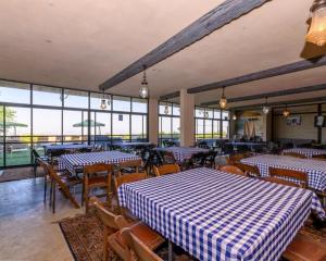 an empty restaurant with tables and chairs and windows at האלפים של הכרמל ומצפה העמקים- וילה ומלונית מול נוף הצפון in Talpiyyot
