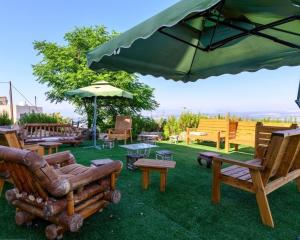 a patio with chairs and an umbrella and tables at האלפים של הכרמל ומצפה העמקים- וילה ומלונית מול נוף הצפון in Talpiyyot