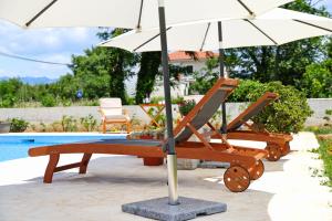 two chairs and an umbrella next to a pool at Pomalo in Vrsi