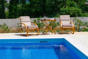 two chairs and a table next to a swimming pool at Pomalo in Vrsi