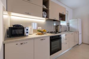a kitchen with white cabinets and a microwave at Pomalo in Vrsi
