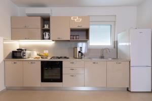 a kitchen with white cabinets and a refrigerator at Pomalo in Vrsi