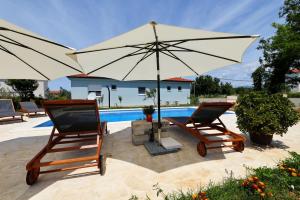 two chairs and an umbrella next to a pool at Pomalo in Vrsi +33 photos