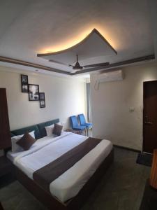 a bedroom with a large bed and blue chairs at HOTEL RAJBHOG indore in Indore +9 photos