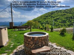 a stone barrel sitting in the grass with a bench at Domek w Chmurach in Kicznia