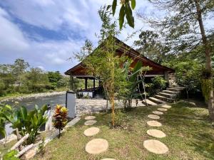 a building with a small tree next to a river at Asim Paris Guesthouse & jungle trekking in Bukit Lawang