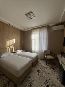 a hotel room with two beds and a chair at Bahrom Boutique Hotel in Khiva