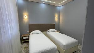 two twin beds in a small room with at Bahrom Boutique Hotel in Khiva