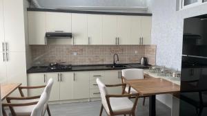 a kitchen with white cabinets and a wooden table and chairs at Bahrom Boutique Hotel in Khiva