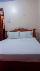 a bed with white sheets and pillows in a room at Dee Holiday Homes Studio-Bamburi Total in Mombasa