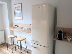 a white refrigerator in a kitchen with two stools at Chic Alpine Oasis in Oberammergau with Mountain View in Oberammergau