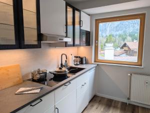 a kitchen with white cabinets and a sink and a window at Chic Alpine Oasis in Oberammergau with Mountain View in Oberammergau