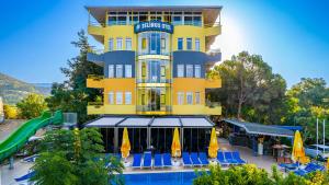 a yellow building with a pool and a playground at Selinus Beach Club Hotel in Gazipasa