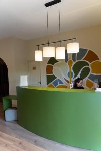 a woman sitting at a green counter in a room at Logis Hostellerie De L'Abbaye in Le Thoronet