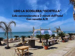a beach with tables and chairs and the ocean at Hotel Paradiso in Lago Patria