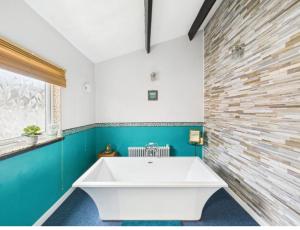 a bathroom with a white tub and a brick wall at The Bishop Bolthole in Bishop Auckland
