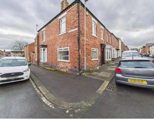 two cars parked in front of a brick building at The Bishop Bolthole in Bishop Auckland