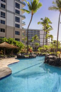a swimming pool with palm trees and a building at Marriott's Maui Ocean Club - Molokai, Maui & Lanai Towers in Lahaina