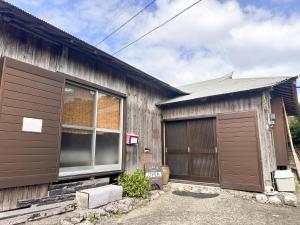 a wooden building with a garage and a window at 民泊Toshi29 in Wadomari