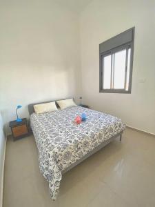 a bedroom with a bed with a blue and white comforter at Penthouse à Manhattan Netivot in Netivot