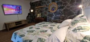a bedroom with a bed and a tv on a wall at Torre Bella Gardens in Arco da Calheta