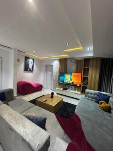 a living room with two couches and a flat screen tv at The Adun Grove in Lekki