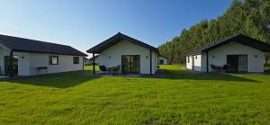 a view of two houses with green grass at Brydar with Sauna, Swimming Pool and Jacuzzi in Mielno