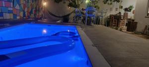 a blue swimming pool in a room with chairs at Happy GUEST House Beto Carrero in Navegantes