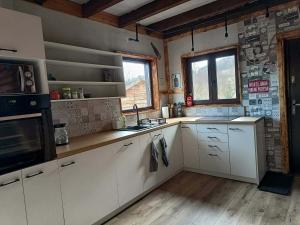 a kitchen with white cabinets and a stove top oven at Enklawa w Porębie in Długopole-Zdrój