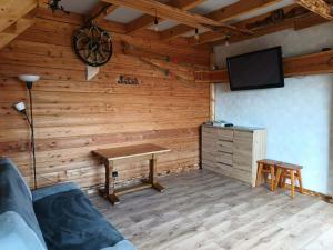 a room with a wooden wall with a table and a tv at Enklawa w Porębie in Długopole-Zdrój