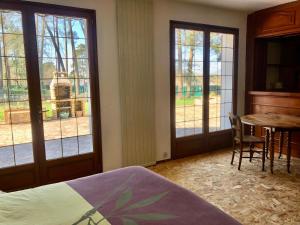 a bedroom with a bed and a table and windows at Le toit d'éco pins in Le Luart