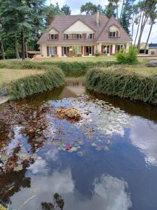 a house with a pond in front of a house at Le toit d'éco pins in Le Luart +4 photos