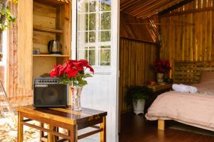 a bedroom with a bed and a vase with red flowers at Làng Hương Village in Teurnoum