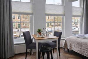 a dining room with a table and chairs and windows at Boutique Hotel De Grote Kade in Goes