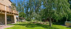 a tree in a yard next to a house at Ferienhof Eiderdeich- Wohnung Gertrud in Delve