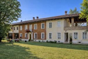 a large brick building with people sitting on a lawn at Guest House La Carolina in Tigliole