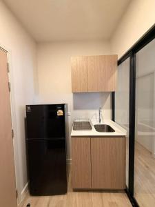 a kitchen with a black refrigerator and a sink at Xim Condo in Bangkok 20 mins to Asiantique in Ban Tha Hin +5 photos