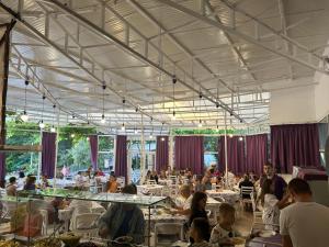 a group of people sitting at tables in a restaurant at Hotel RIVA in Golden Sands