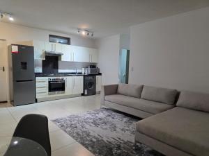 a living room with a couch and a kitchen at Prestige stays in Windhoek