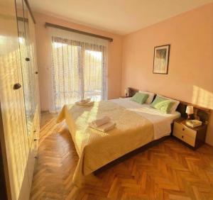 a bedroom with a large bed with a wooden floor at Apartment Novi II in Kaštela
