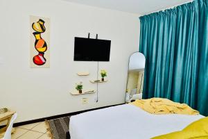 a bedroom with a bed with blue curtains and a tv at Cozy Comfortable Apartment with pool in Pretoria +15 photos