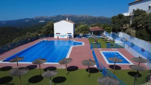 a large swimming pool with umbrellas on the side of a building at Casa Rural "Baru" in Alpandeire