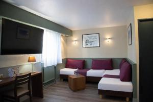 a living room with a couch and a table at The Originals City, Hôtel Ascotel, Lille Est Grand Stade in Villeneuve d'Ascq