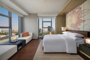 a bedroom with a large white bed and a couch at Courtyard by Marriott Luoyang in Luoyang +22 photos