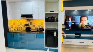a kitchen with blue cabinets and a tv on the wall at Elevenstay in Ghaziabad +10 photos