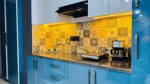 a kitchen with blue cabinets and a yellow tiled wall at Elevenstay in Ghaziabad