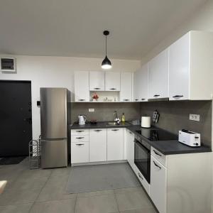 a kitchen with white cabinets and a stainless steel refrigerator at M&M Cozy Apartment-Free Parking in Skopje