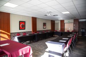 a conference room with black tables and red chairs at The Originals City, Hôtel Ascotel, Lille Est Grand Stade in Villeneuve d'Ascq